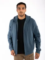 Campera canguro Kevingston de jersey frisado invisible de algodón, en color azul. Presenta cierre frontal completo, capucha con cordón ajustable y bolsillos delanteros amplios tipo canguro.