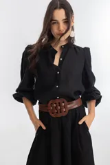 Cinturón de cuero vacuno color marrón con diseño trenzado circular en el frente y cierre elástico en la parte trasera con botones a presión.