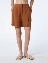 Short color marrón con bolsillos delanteros y cierre con broches ocultos. Elástico en la pretina trasera.