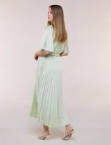 Vestido maxi de satén color rosado, con escote en V cruzado, mangas cortas amplias, cintura elastizada con lazo de ajuste y falda plisada con forro interno.