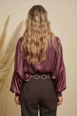 Blusa de satén color champagne con cuello a la base, mangas anchas y puños elásticos con detalle bordado.