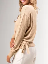 Sweater color beige de bremer, tejido fino, con escote cruzado en V y mangas largas.