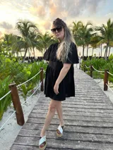 Vestido corto color beige de lino, con cuello mao, mangas cortas con volados, tablas en el canesú y falda escalonada con volantes.