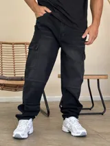 Pantalón tipo cargo de denim color negro con efecto lavado. Presenta corte holgado, bolsillos laterales con solapa y costuras reforzadas en las rodillas.