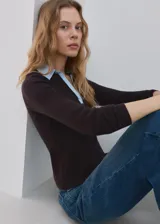 Chaleco de punto grueso color marrón, con diseño entallado, cuello camisero celeste en contraste y mangas largas.