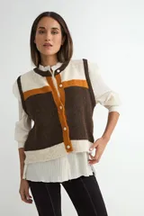 Chaleco tejido de punto con diseño de bloques de color en tonos marrón, naranja y crema. Presenta cuello redondo, cierre frontal con botones y terminaciones acanaladas en el ruedo y sisas.