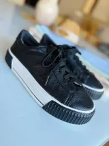 Zapatillas urbanas de cuero negro con cordones y plataforma blanca con suela negra.