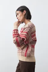 Sweater de punto con diseño jacquard de inspiración nórdica, cuello redondo y mangas largas. Presenta un patrón geométrico en tonos tierra, azul y blanco, con puños y ruedo acanalados.