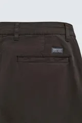 Pantalón chino de corte ajustado, color beige, con bolsillos laterales y bolsillos traseros de vivo. Cuenta con cierre frontal de cremallera y botón.