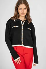 Saco corto de punto color negro con cuello polo, cierre frontal con botones dorados y ribete blanco en cuello, puños y ruedo.