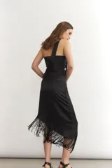 Vestido midi sin mangas color turquesa, con escote strapless y detalle de nudo frontal. El ruedo presenta un corte asimétrico con flecos negros largos.