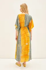 Vestido midi de estilo boho, confeccionado en viscosa con paneles alternados en colores amarillo y verde grisáceo. Presenta un estampado floral con detalles bordados en hilo de lurex, escote en V profundo, mangas anchas al codo y ajuste elástico en la cintura.