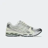 Championes Asics Gel-Kayano 14, inspirados en el diseño de 2008, confeccionados con malla transpirable y revestimientos metálicos plateados y beige. Incorporan tecnología GEL en la suela para mayor amortiguación.