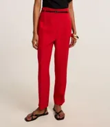 Pantalón de sastrería corte carrot, color beige, con cintura alta, pinzas frontales y cinturón fino incorporado con hebilla metálica.