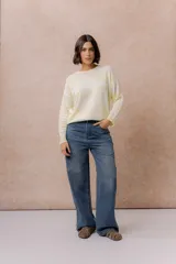 Jean wide leg de tiro medio-alto en denim azul medio con lavado desgastado. Presenta diseño de cinco bolsillos, cierre con botón y cremallera, y pierna amplia de caída recta.