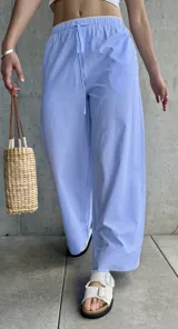 Pantalón pijamero celeste a rayas verticales blancas, de corte ancho y cintura con cordón ajustable.