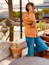 Cárdigan tejido color tostado, de lana, con cuello redondo y abotonadura frontal.