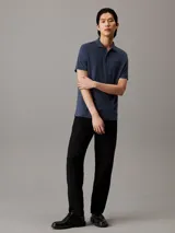 Chomba azul de corte slim confeccionada en algodón orgánico, con cuello clásico, tapeta de dos botones, mangas cortas con puños de punto, aberturas laterales y logo bordado en el pecho.