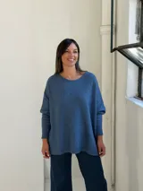 Sweater de punto color azul, con cuello redondo, corte holgado y mangas largas con puños ajustados.