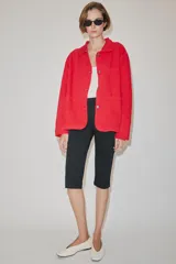Chaqueta oversize de corte recto en color rojo, con cuello solapa, manga larga y bolsillos de parche delanteros. Cuenta con cierre frontal de botones metálicos y pespuntes a contraste.