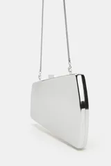 Bolso tipo clutch rígido con acabado metálico dorado y diseño geométrico. Incluye cadena metálica extraíble y cierre de doble clip.