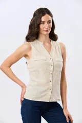 Musculosa de lino color beige, con cuello mao y escote en V, cierre frontal con botones y dos bolsillos plaqué con solapa en el pecho.