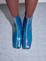 Bota de caña media en cuero negro con punta cuadrada y taco de madera. Cuenta con una costura bordada en color contrastante en el empeine y cierre en la parte trasera.