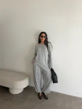 Conjunto gris melange compuesto por un buzo de cuello bote amplio y corte asimétrico con bolsillos, y un pantalón largo de corte recto y holgado.
