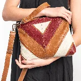 Bolso tipo sobre con correa larga ajustable y removible, y asa de mano corta. Diseño con paneles geométricos en cuero color caramelo, arena y rojo.