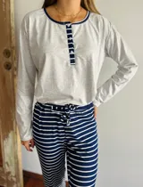 Pijama de algodón compuesto por una remera gris de manga larga con cuello redondo y tapeta de botones azul marino, y un pantalón largo a rayas horizontales azul marino y blanco con cintura elastizada y lazo de ajuste.