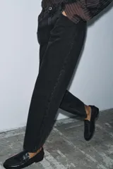 Jeans de tiro medio con corte slim leg, confeccionados en denim color beige. Presentan cintura con trabillas, diseño clásico de cinco bolsillos y cierre frontal con cremallera y botón metálico.