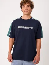 Remera de manga corta Rusty modelo Zoren S27, de color azul marino con bloques de color verde en las mangas, líneas blancas decorativas en los hombros y logo estampado en el frente.