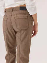 Jean de corte recto confeccionado en denim azul oscuro, con costuras a la vista en color rojo contrastante. Presenta un diseño de tiro alto con bolsillos frontales y cierre de botón.