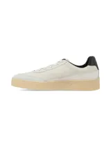 Championes de estilo urbano en color crema con detalles en negro. Presentan un diseño con logo lateral curvo, puntera de gamuza y suela de goma texturizada en tono natural.