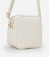 Cartera bandolera Satinato pequeña de color blanco, de diseño estructurado con textura floater, cierre de cremallera y detalles metálicos dorados. Incluye una correa larga ajustable y un pompón decorativo colgante.