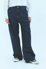 Pantalón de jean azul denim con tiro bajo, corte oversize y grabado láser con monograma.