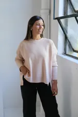 Sweater de tejido de punto color crudo, con cuello redondo, mangas largas y diseño holgado con aberturas laterales en el ruedo.