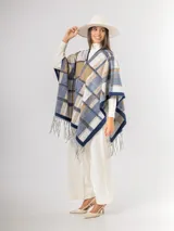 Ruana abierta con diseño de cuadros en tonos azul, beige y blanco, con terminación de flecos en el ruedo.