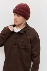 Buzo de friza de algodón marrón con capucha, cuello tipo polo con botones y un bolsillo frontal con solapa en el pecho.