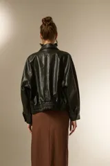 Campera estilo biker de eco-cuero color bordó, con cuello solapa ancho, manga larga y calce holgado. Presenta cierre frontal y botones decorativos en la parte inferior delantera.