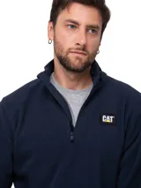 Buzo polar de microfibra color azul marino, con cuello alto y cierre frontal de cuarto de longitud. Presenta el logo de la marca Caterpillar aplicado en el pecho.