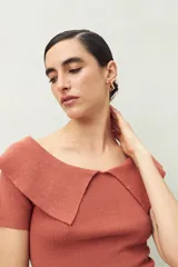 Top tejido en punto acanalado color terracota, de manga corta y escote amplio que cae sobre los hombros.
