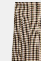 Pantalón tobillero de tiro alto con estampado de cuadros pequeños en tonos beige y negro. Presenta costuras marcadas en el delantero y la espalda, bolsillos laterales de vivo y cierre frontal con cremallera, botón interior y gancho metálico.