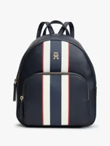 Mochila urbana de diseño estructurado en color azul marino, con franjas verticales en blanco y rojo en el centro. Presenta el logo monograma TH metalizado en la parte superior, bolsillo frontal con cierre y herrajes dorados.