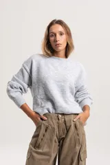 Buzo tejido de punto con diseño liso, corte oversize, cuello redondo y mangas largas con puños acanalados.