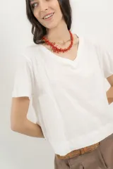 Remera blanca de algodón orgánico, con escote en V, mangas cortas y corte A-line. Cinta aplicada en la espalda con bordado de palmera.