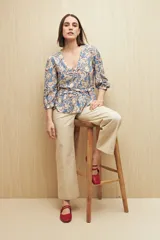 Blusa celeste con estampado floral en tonos beige y marrón, escote en V, mangas 3/4 abullonadas y frunce en la cintura.