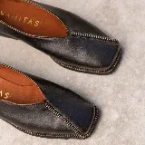 Zapato bajo de cuero negro con punta cuadrada y detalle de cierre en la capellada.