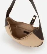 Cartera tipo baguette de diseño curvo, confeccionada en material sintético efecto gamuza color beige con detalles de costuras decorativas en los bordes y apliques en cuero sintético marrón. Cuenta con cierre superior, correa de hombro y herrajes metálicos en tono dorado claro.