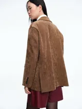 Blazer de pana color marrón con solapas clásicas, cierre frontal de dos botones y bolsillos laterales con solapa.